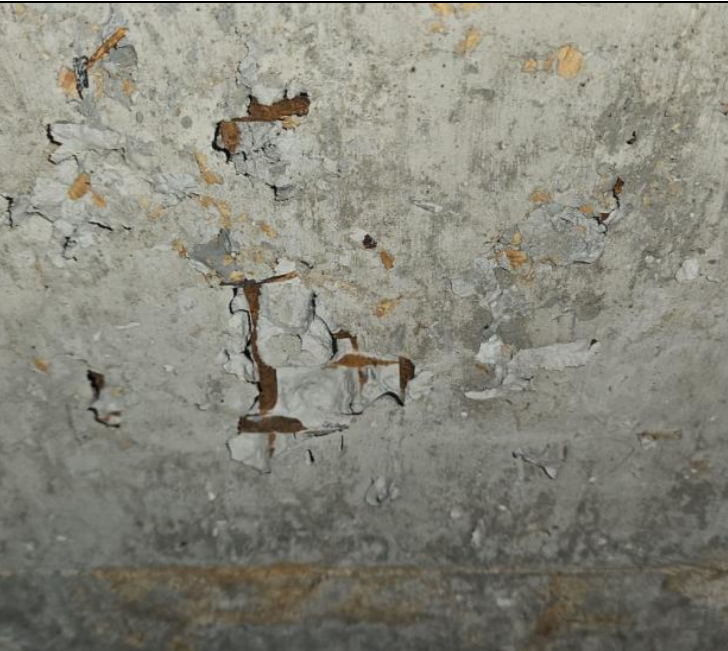 Armadura exposta com sinais de corrosão em elemento de concreto, associada ao desplacamento do cobrimento.