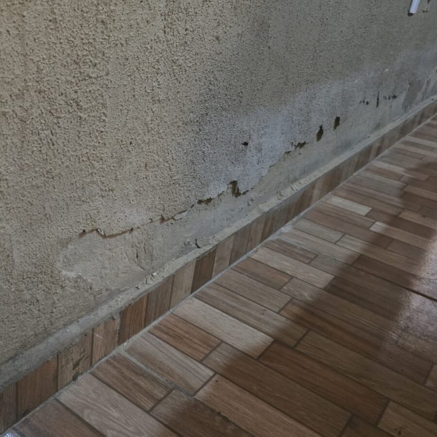 Descascamento de pintura e degradação do revestimento em parede interna com sinais de umidade na base.