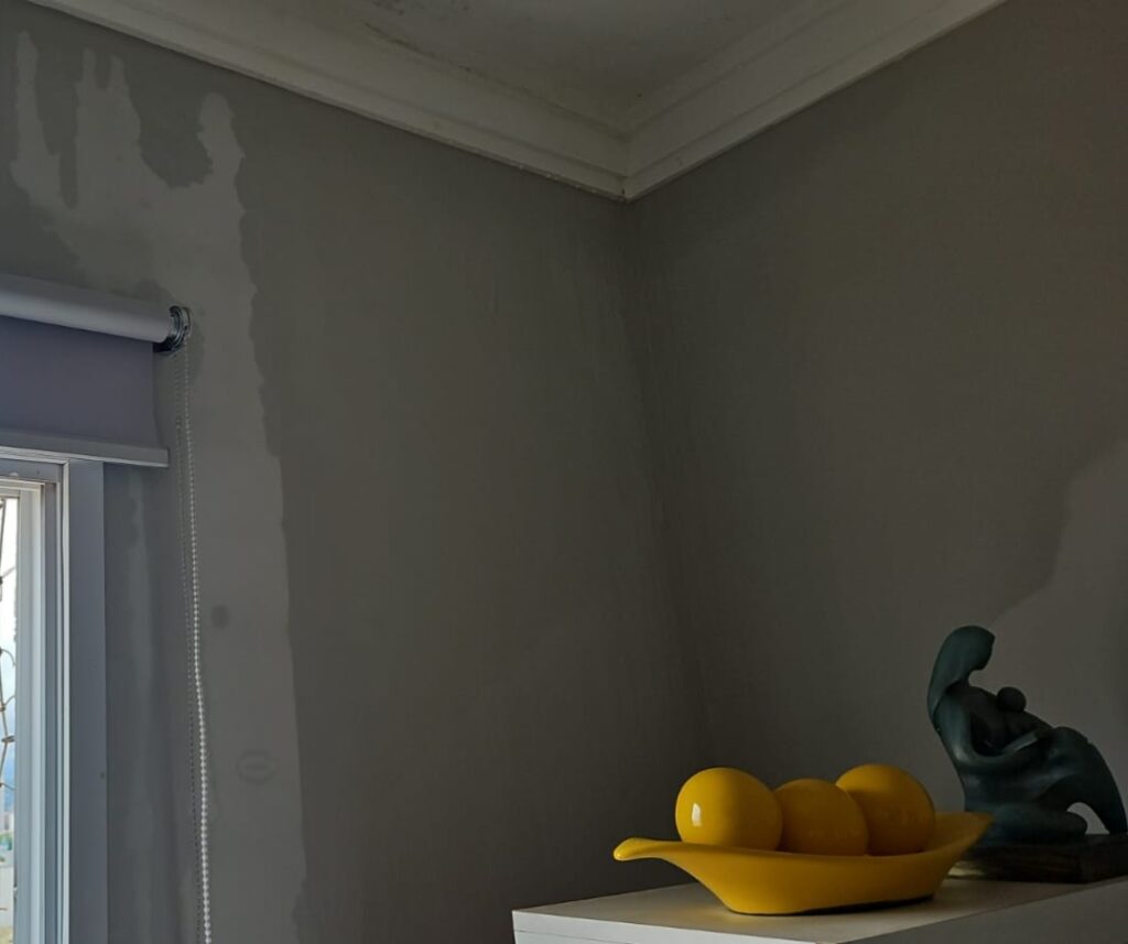 Mancha de infiltração de cobertura em parede interna próxima à janela, com sinais de umidade descendente no revestimento e pintura.