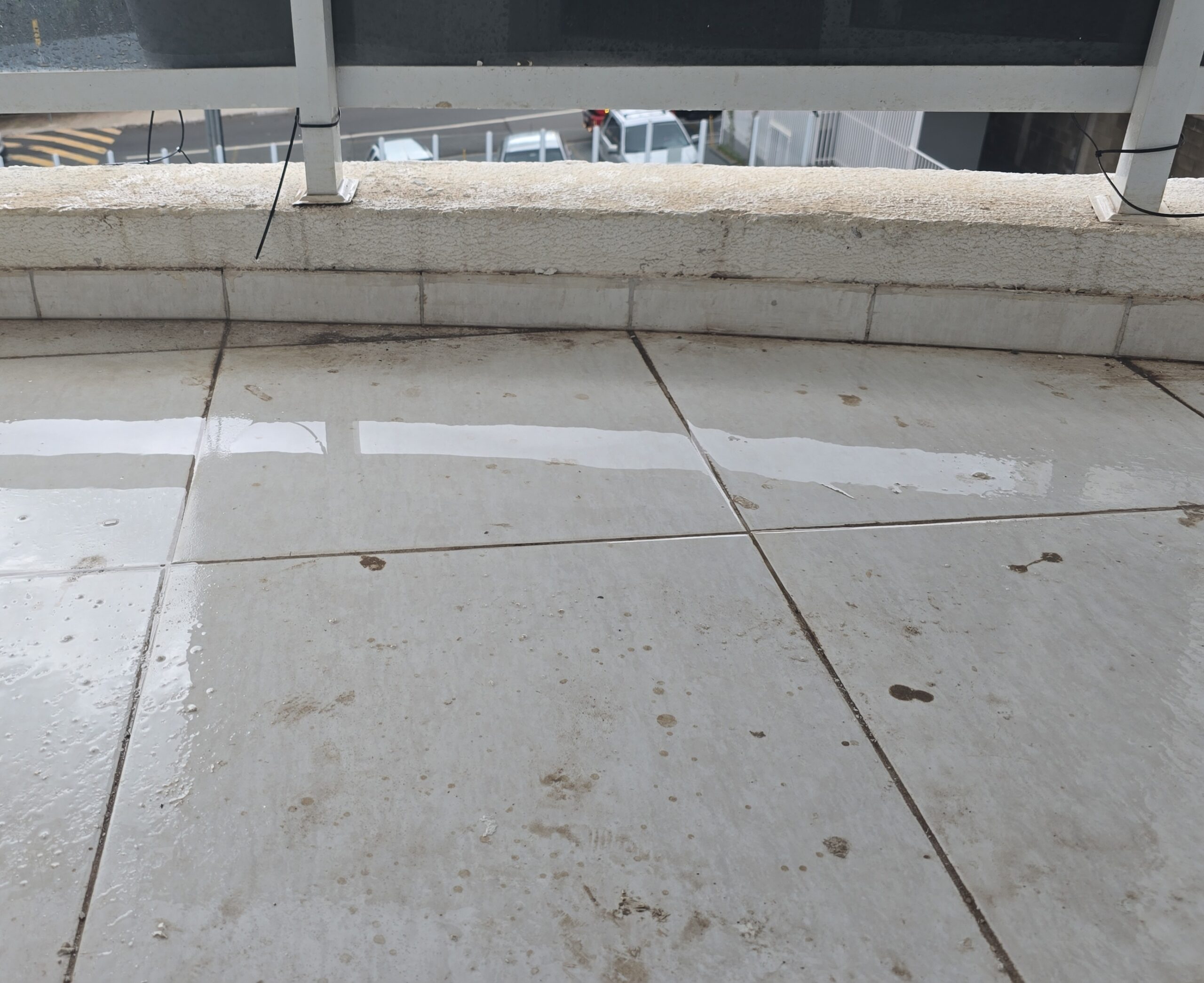 Piso de varanda com acúmulo de água por queda invertida, observado durante vistoria técnica de locação.