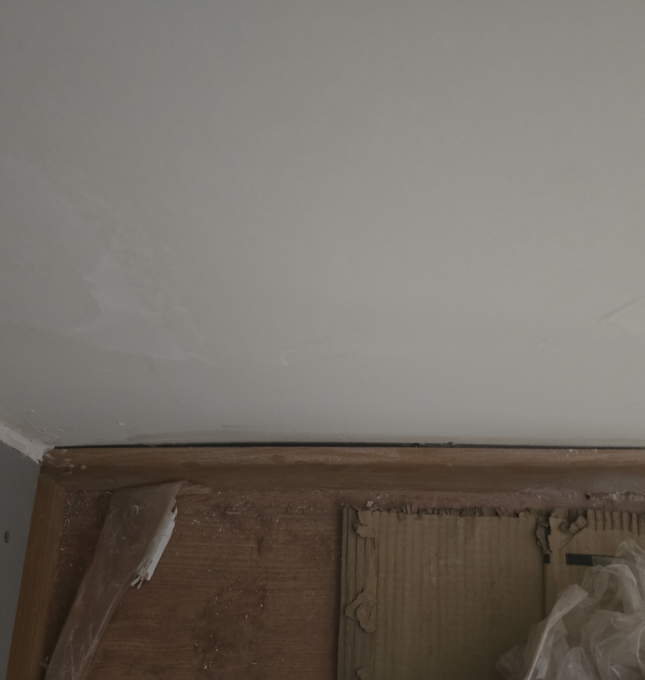 Rodapé desplacando em quarto durante vistoria de locação, com falha de aderência próxima à janela.