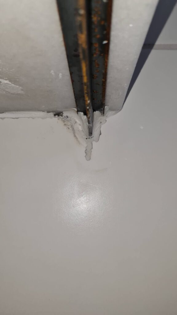 Fixação metálica de bancada com sinais de corrosão e falha de acabamento observada durante vistoria técnica.