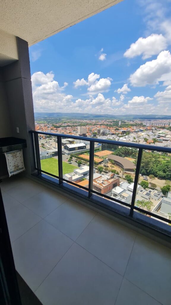 Sacada de apartamento com guarda-corpo de vidro, piso cerâmico e vista panorâmica avaliados durante vistoria técnica.
