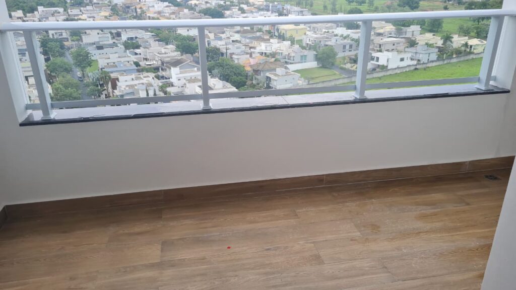 Sacada de apartamento com piso amadeirado, guarda-corpo e vista externa avaliada durante vistoria técnica.