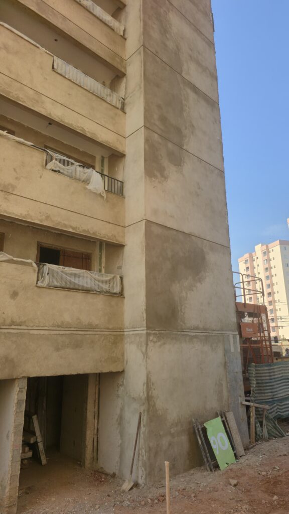 Fachada com janelas, manchas e marcações de inspeção em edifício em construção.